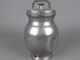 an old silver pot with a lid on a gray surface