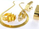un collier, un bracelet et une bague en or posés sur une surface blanche