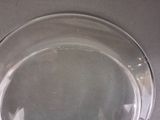 a clear glass plate with a black handle on a table