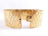 a close up of a gold bracelet with a lock on a white surface