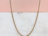 un collier à chaîne en or posé sur une surface en marbre