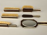cinq brosses en bois et un miroir posés sur une table