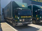 two green trucks parked in front of a building with a sign on the side