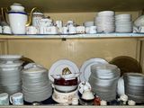 many plates and cups on a shelf in a cabinet