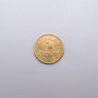 gros plan d'une pièce d'or sur une surface blanche