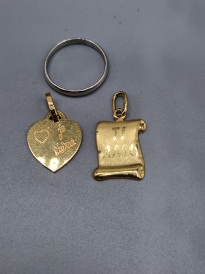 deux bijoux en or et en argent posés sur une surface grise
