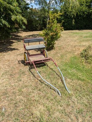 un petit chariot muni d'un tuyau, posé dans l'herbe