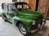 une voiture verte garée dans un garage dont la porte est en bois