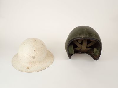 two helmets are sitting on a white surface, one is green and the other is white
