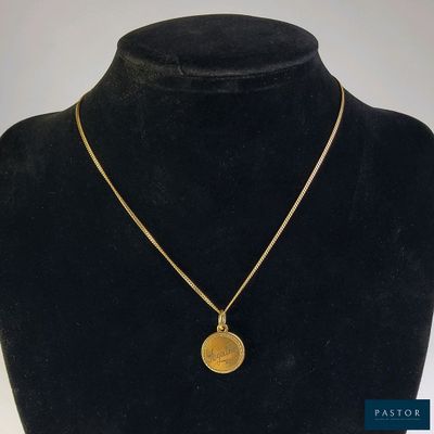 un collier en or avec une pièce de monnaie sur le cou d'un mannequin