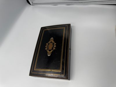 un petit livre noir aux bords dorés posé sur une table blanche