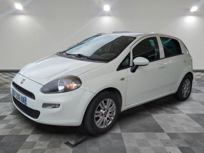 La petite voiture blanche est garée dans le garage, sur le sol à carreaux.