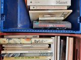 une pile de livres dans une boîte en plastique posée sur une étagère