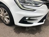 the front end of a white car parked on the side of the road