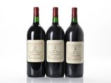 trois bouteilles de vin rouge posées l'une à côté de l'autre sur une surface blanche