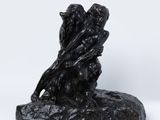 une photo représentant une statue de deux personnes assises sur un rocher