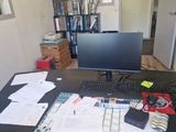 a desk with a computer, keyboard, mouse, and papers on it