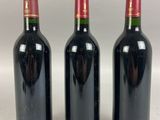 three bottles of wine are lined up on a white surface