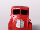 a red toy truck with a white top on a white surface