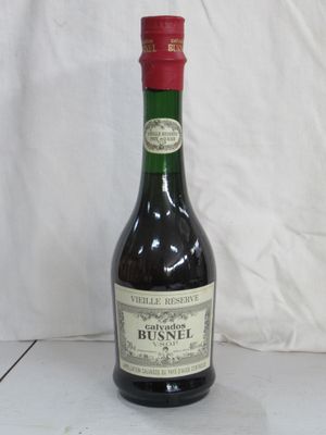 Des bouteilles de vin sont posées sur une surface blanche, devant un fond blanc.