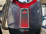 someone is holding a red and black steam cleaner in a store