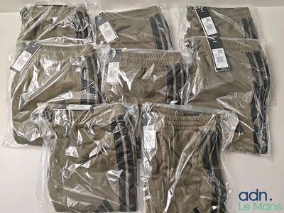 six paires de pantalons pour homme, emballées dans des sacs en plastique, posées sur une table