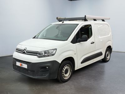 La camionnette blanche est garée dans une grande pièce au toit plat.