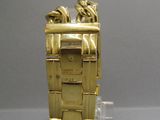a gold watch that is sitting on a clear stand