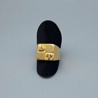 une bague en or posée sur un porte-bague noir, sur une surface blanche