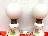 une paire de lampes blanches ornées de fleurs violettes, posées sur un tissu rouge
