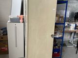 a refrigerator in a room with a lot of boxes on the shelves