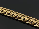 gros plan d'un bracelet en or sur une surface noire