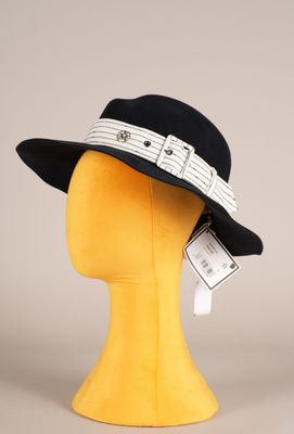 Le chapeau est noir et blanc, avec un ruban qui l'entoure.