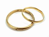 two gold wedding rings on a white surface