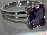 une bague ornée d'une pierre violette, posée sur une table