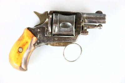 un vieux revolver avec une poignée en bois sur une surface blanche