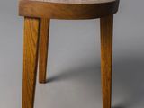 a close up of a wooden stool on a gray surface
