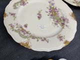 four plates with purple flowers on them sitting on a table