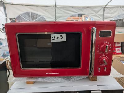 un micro-ondes rouge posé sur une table blanche