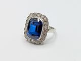 an image of a ring with a blue stone surrounded by white diamonds