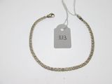 un bracelet en argent muni d'une plaque, posé sur une surface blanche