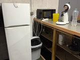 un réfrigérateur et un micro-ondes dans une pièce recouverte d'une moquette verte