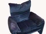 dark blue velvet armchair with pillows and a pillow on the back