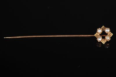 un gros plan d'une broche en or ornée de perles sur fond noir