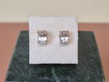 a pair of diamond stud earrings sitting on top of a marble block