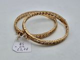 a close up of two gold bracelets on a white surface