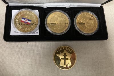trois pièces d'or dans une boîte noire ornée d'une croix et d'une médaille