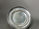 a small silver plate on a stand on a table