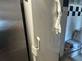 un réfrigérateur blanc dans un coin d'une pièce dont le mur est à carreaux noirs et blancs