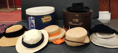 Plusieurs chapeaux sont alignés sur une table à côté d'un seau